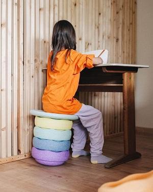 Kindje aan bureau met als stoel stapelstenen