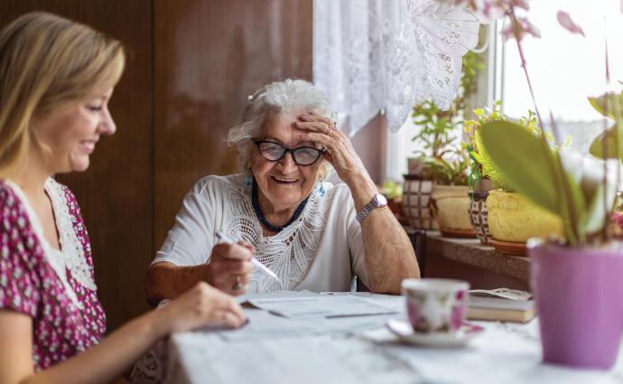 Een zorgverlener geeft een oudere vrouw persoonlijk advies aan huis over veilig en comfortabel wonen.
